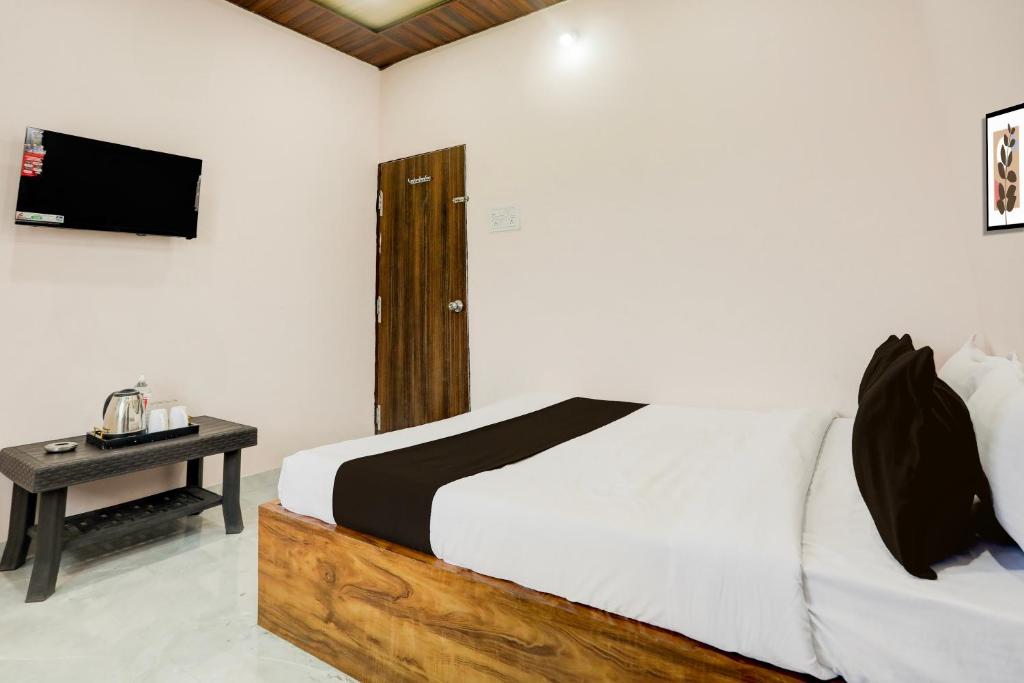 een slaapkamer met een bed en een tafel met een televisie bij HOTEL O SKYLITE Vhirgaon in Pānchgaon