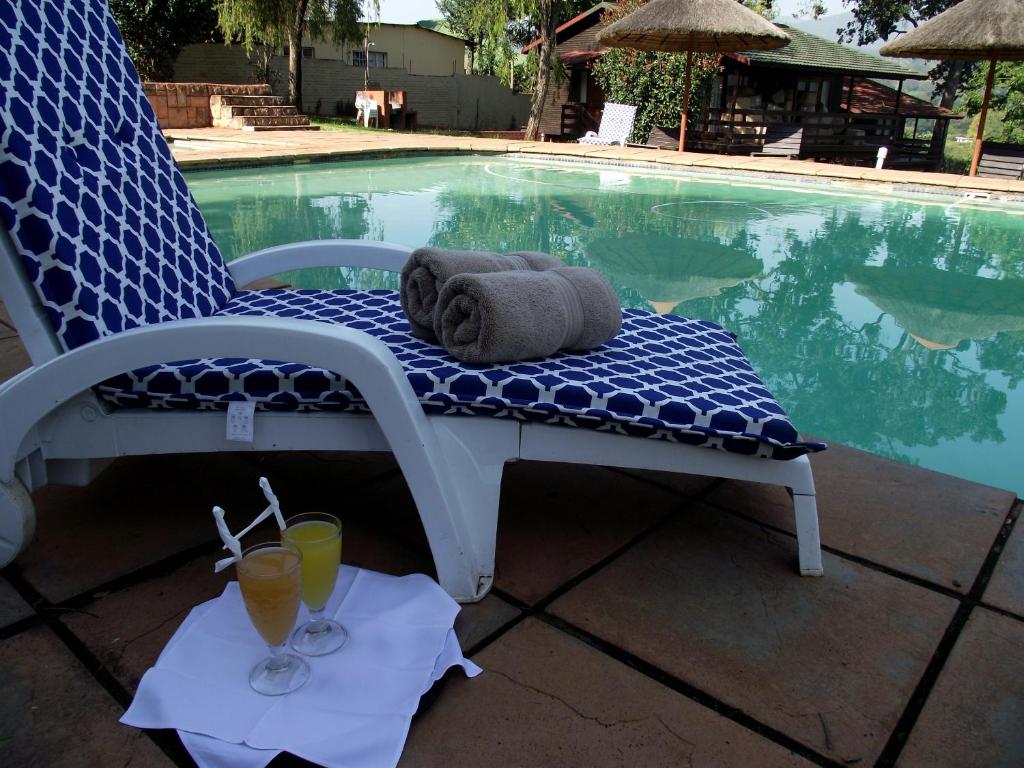 a towel and two drinks on a chair next to a pool at Jock-Sabie Lodge in Sabie