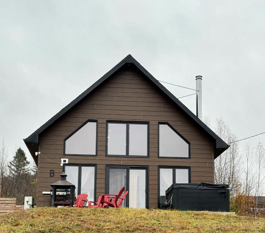 a house with windows and red chairs in front of it at Le Chal'Heureux in Saint Adelphe
