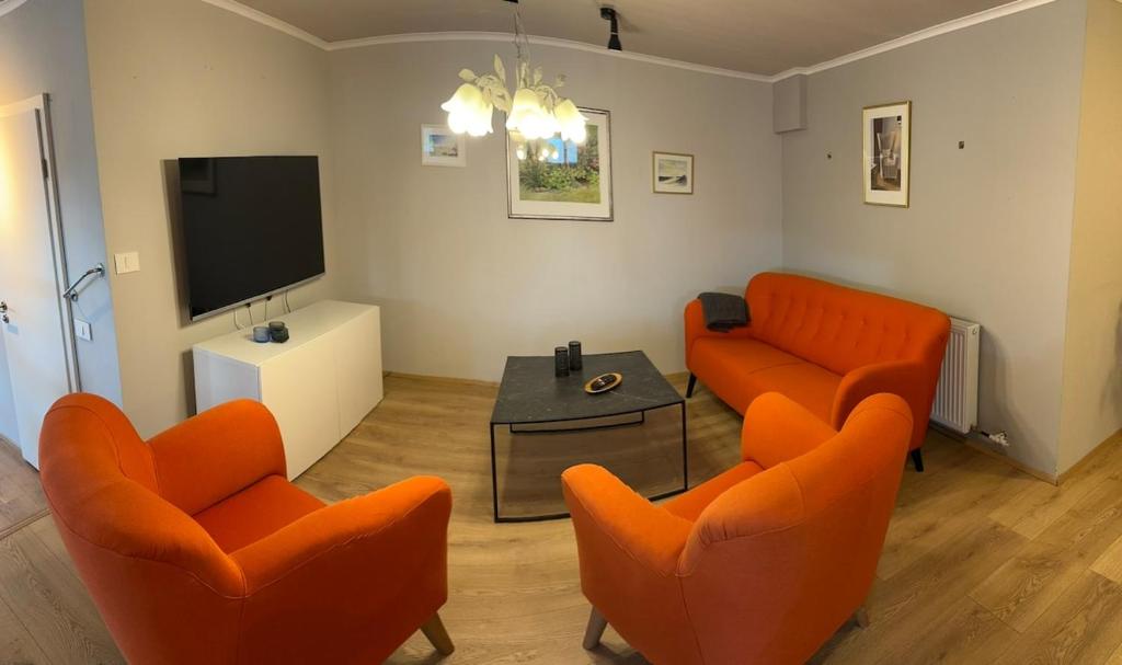 a living room with orange chairs and a flat screen tv at Two rooms apartment in Reykjavik in Reykjavík