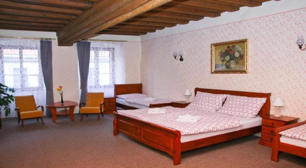 a bedroom with two beds and chairs in a room at Mini Apart Hotel Abraka in Český Krumlov