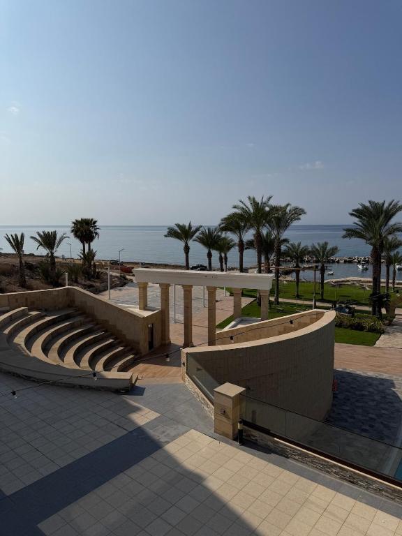 KlorakasにあるCasa Clara Apartment mit Meerblick direkt am Strandのベンチとテーブルとヤシの木がある円形劇場