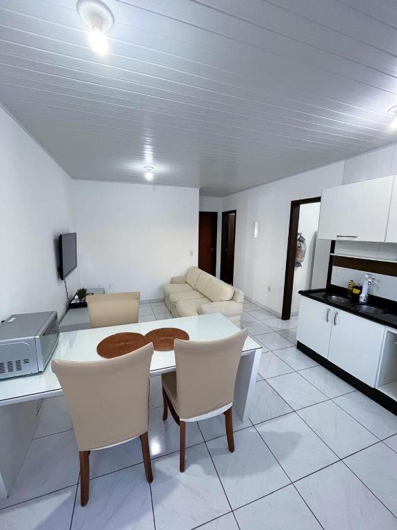 a kitchen and living room with a table and chairs at Apartamento Orquídea in Porto Belo