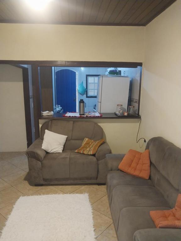 a living room with two couches and a kitchen at CASA DE HOSPEDAGEM FLORES PARATY AMBIENTE FAMILIAR 600M do CENTRO in Paraty