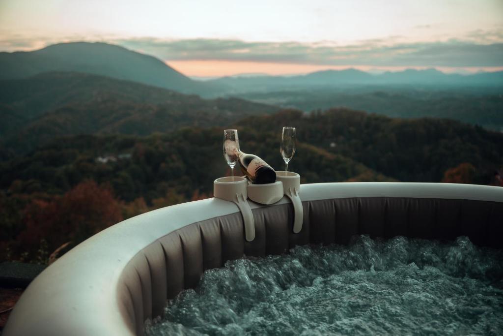 a person holding two glasses of wine on top of a barrel at SkyView Dežno in Makole