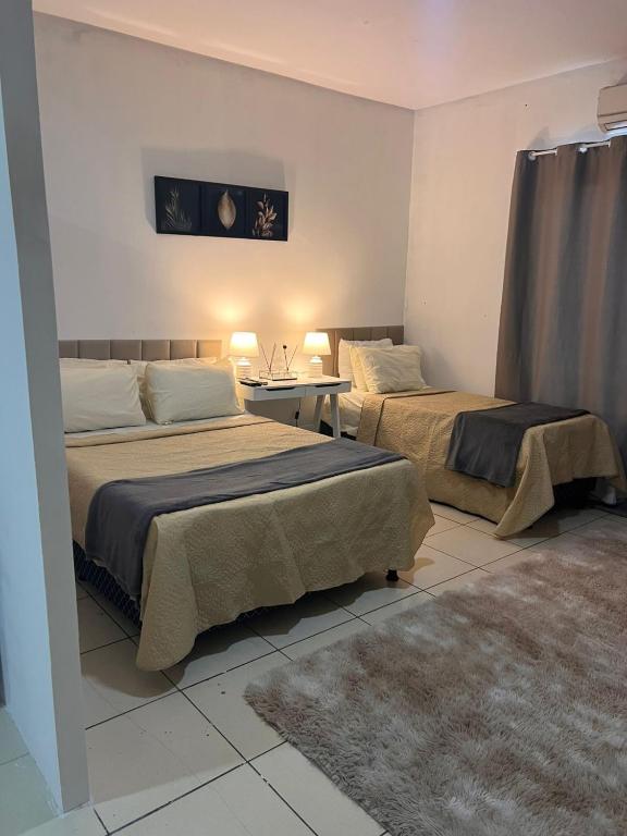 ein Schlafzimmer mit zwei Betten und einem Tisch mit Lampe in der Unterkunft Regency Loft 02 in Petrolina