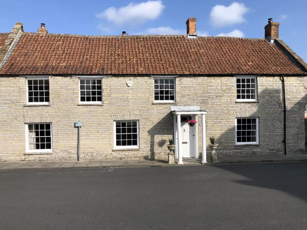 an old brick house with a white door at Old Bell House - Spacious Period Home in the Heart of Somerton in Somerton