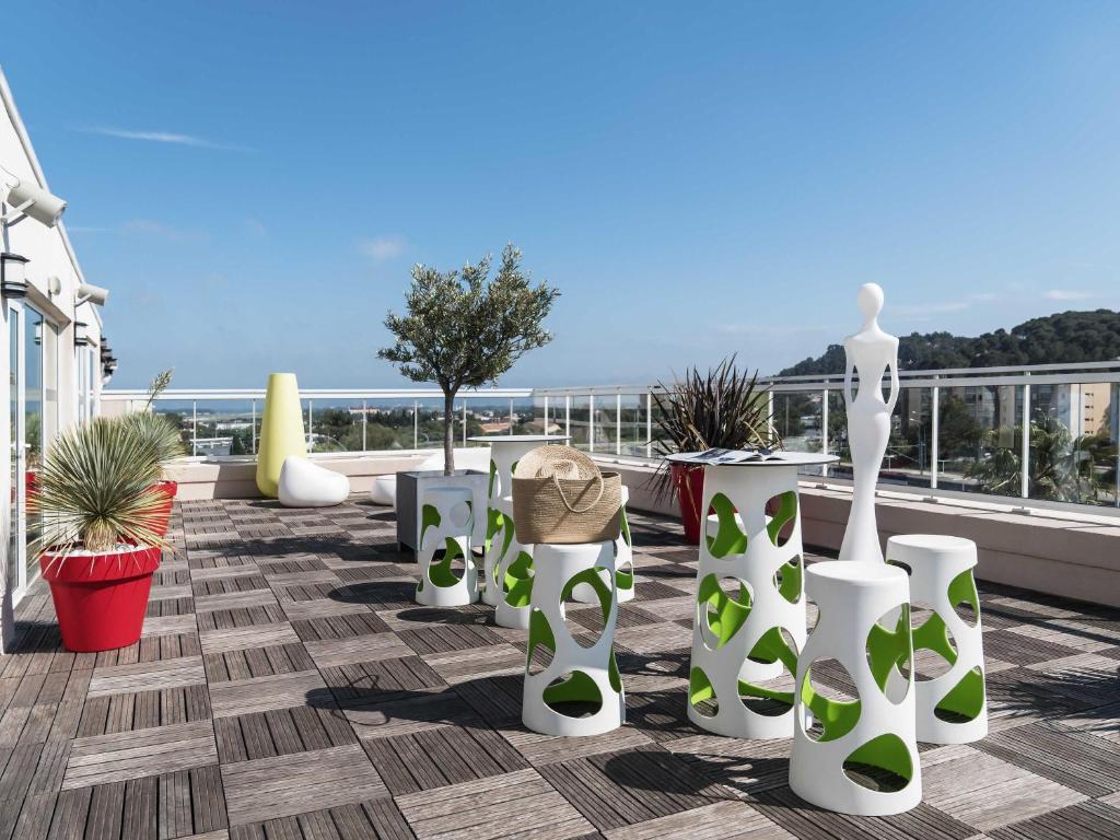 イエールにあるIbis Styles Hyères Rooftop & Spaの白と緑の花瓶と植物が飾られたバルコニー