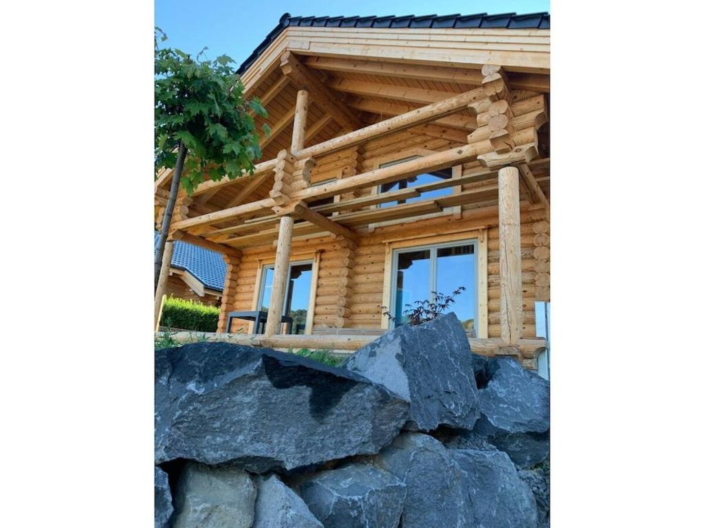 une cabane en rondins avec des rochers devant dans l'établissement Holiday home in Rieden with swimming pool, à Rieden