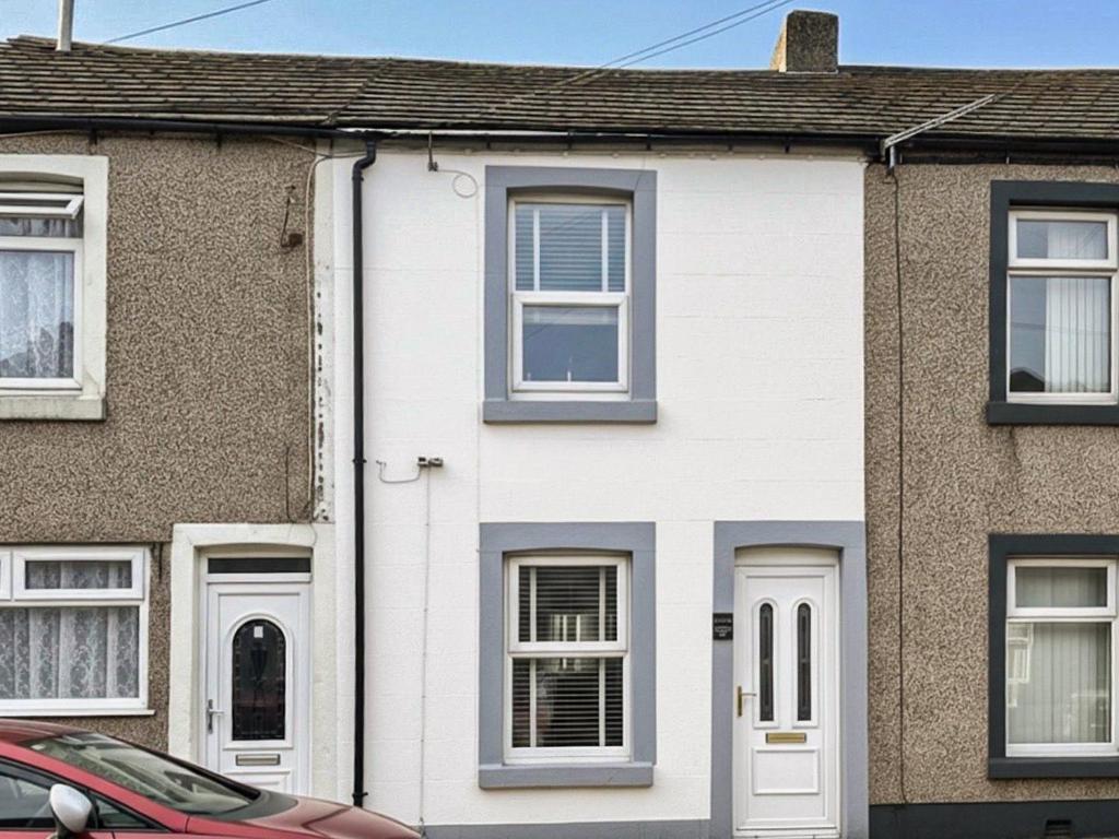 a white house with a car parked in front of it at Miner's Rest in Rowrah