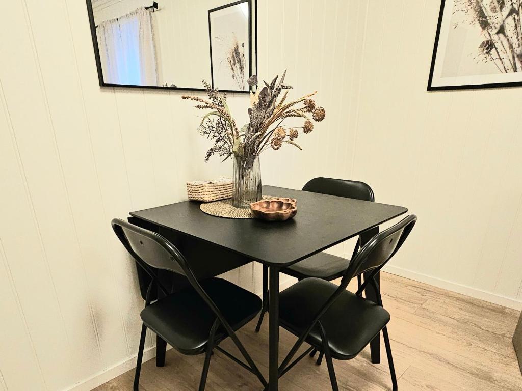 a black table with chairs and a vase with flowers at Fin 3-roms leilighet i Harstad sentrum in Harstad