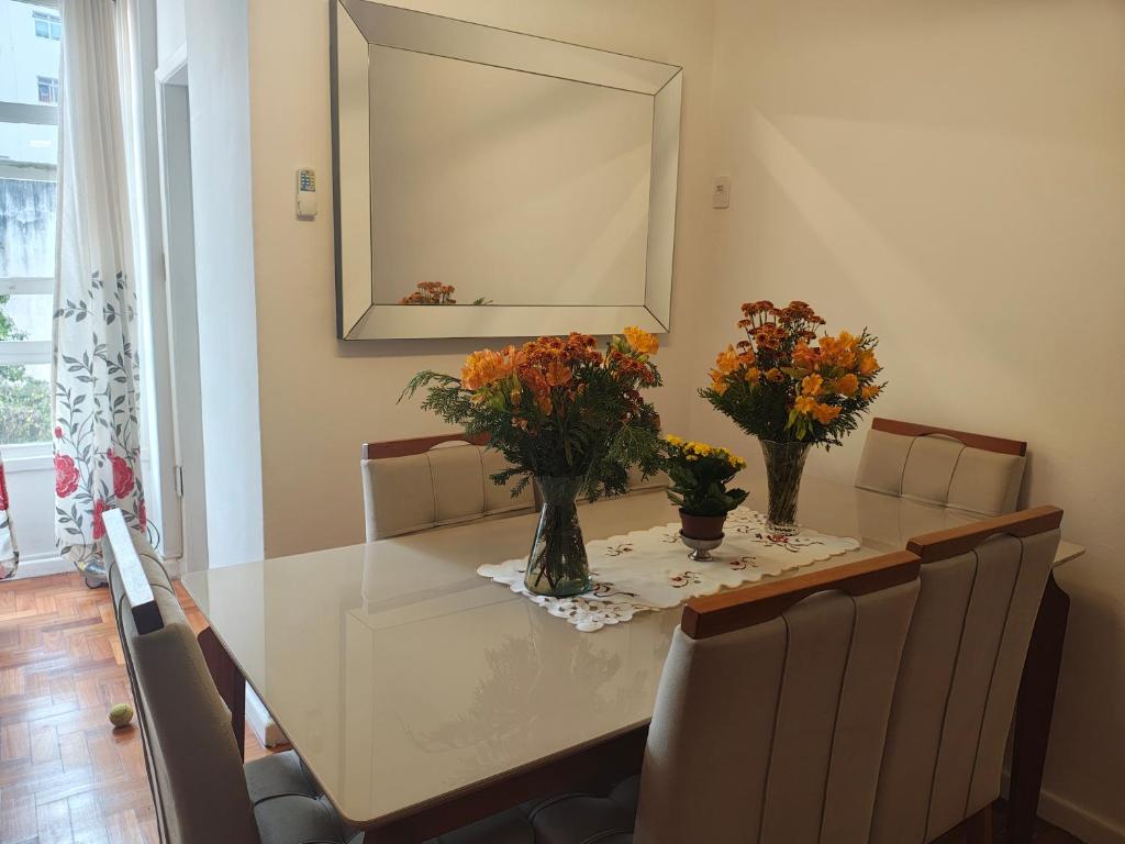 a dining room table with flowers in vases on it at Copacabana - RJ Apto da Gaúcha in Rio de Janeiro