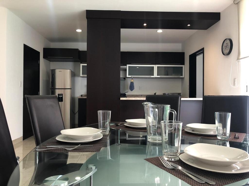 a dining room with a glass table with plates and glasses at House in Private Residential Development Globo-Outlets-Airport in León