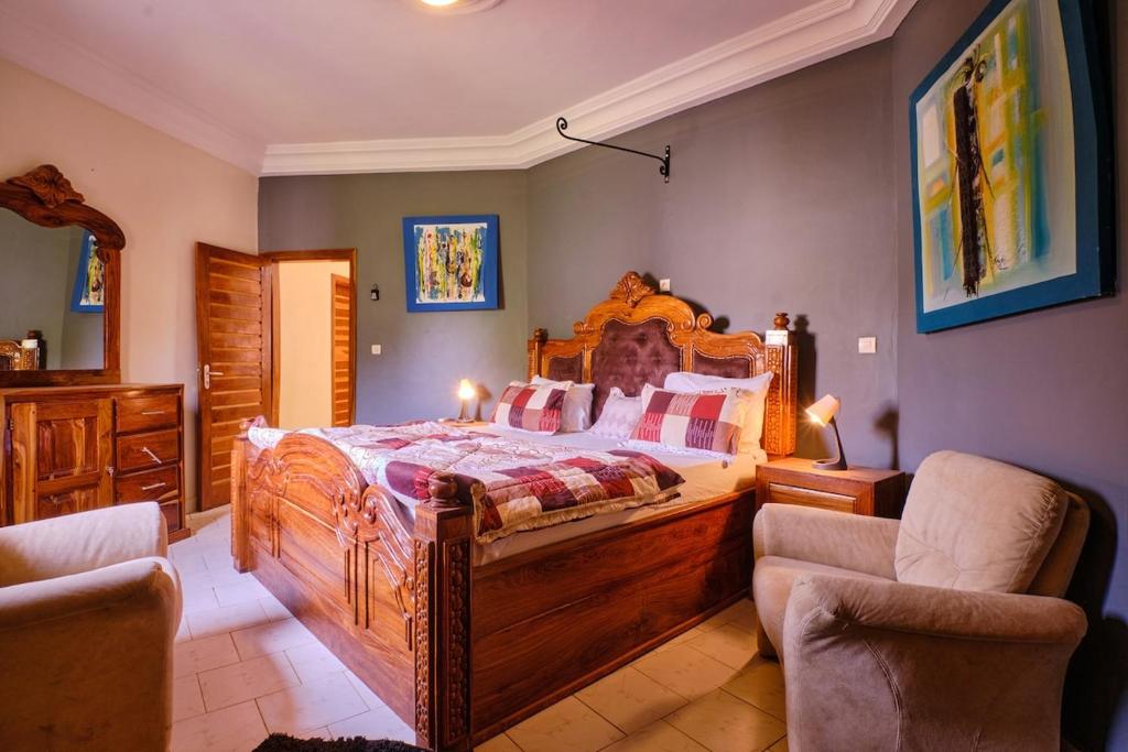 a bedroom with a large wooden bed and two chairs at Elegante villa avec Pool et près de la mer in Mbour