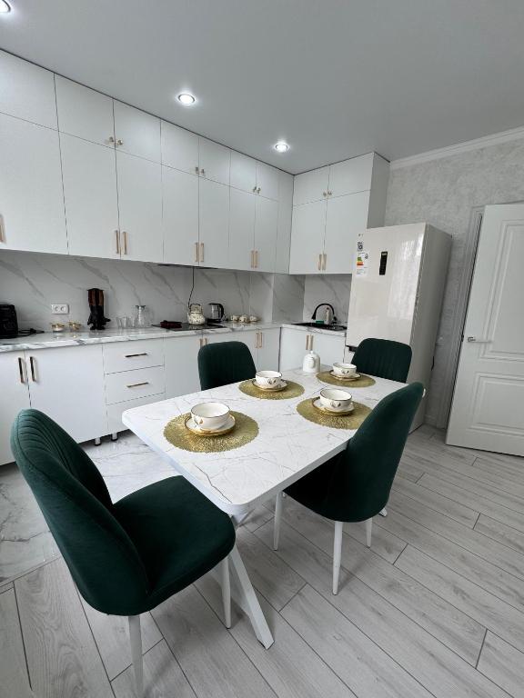 a kitchen with a white table and green chairs at ЖК Арман кала 1- комнатная квартира in Zhezdi