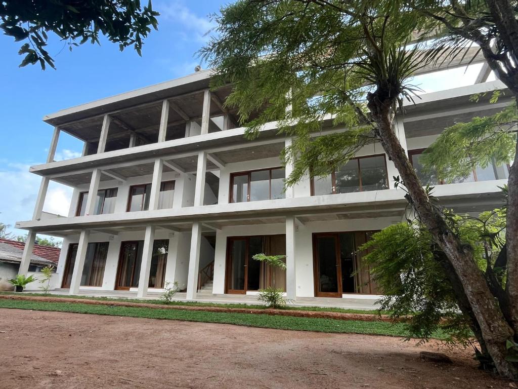 a white building with a palm tree in front of it at Lily Mirissa in Mirissa