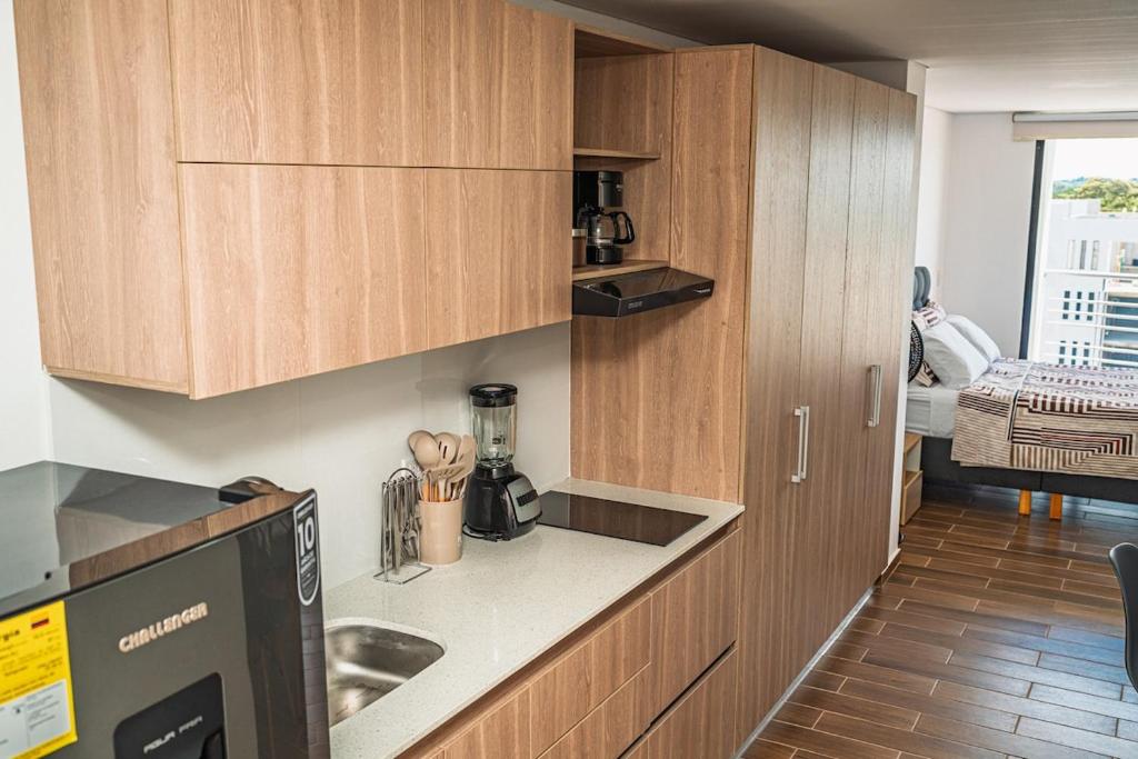 a kitchen with wooden cabinets and a counter top at Modern loft and parking ideal for couples in Acacías