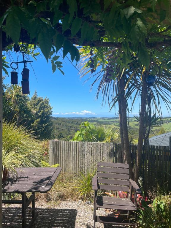een houten bank naast een boom bij First Light in Mangawhai
