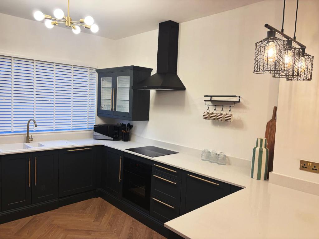 a kitchen with black cabinets and white counter tops at NEW Luxury Neath Center Stay in Neath