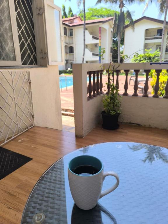 a cup of coffee sitting on a table on a balcony at Poolside Apartment Bliss by the Pool Goa in Candolim