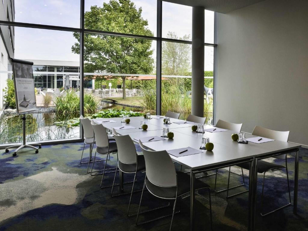 a conference room with a long table and chairs at Mercure Lyon Genas Eurexpo in Genas