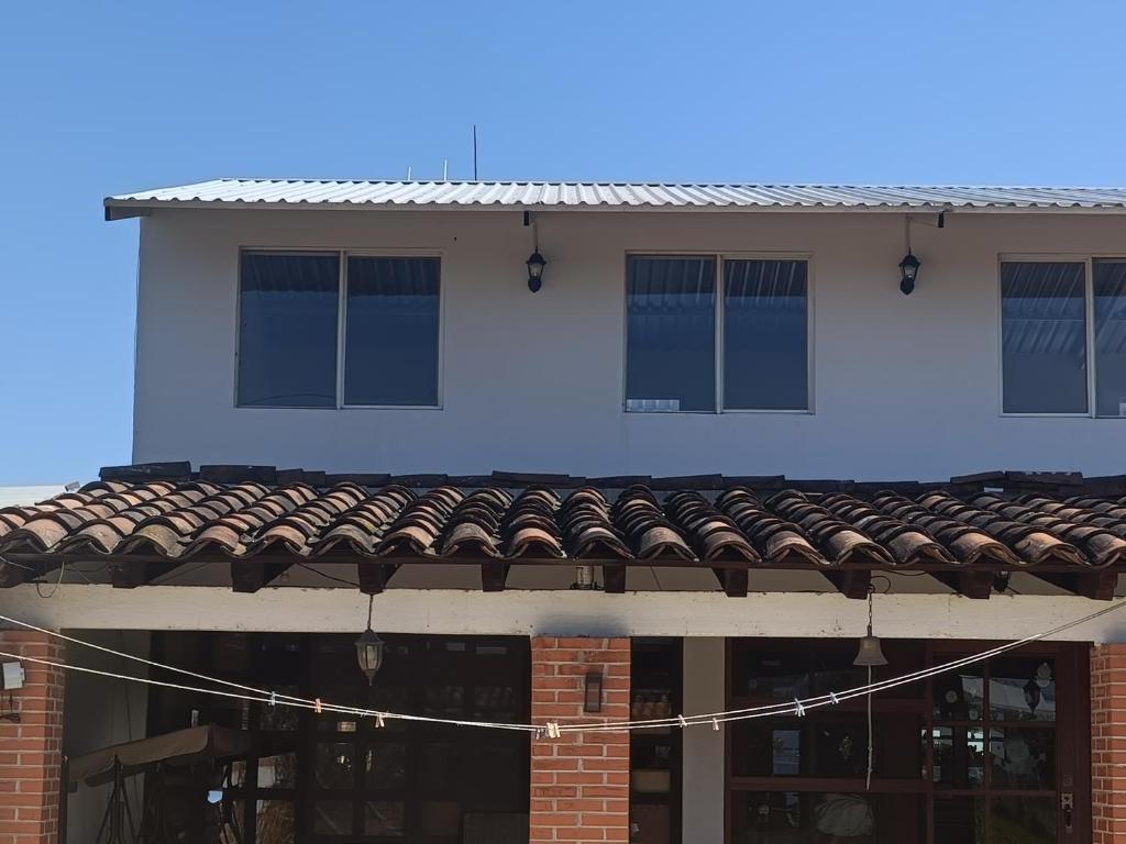 a white building with blue windows and a roof at Hospedaje alcatraz in Chignahuapan