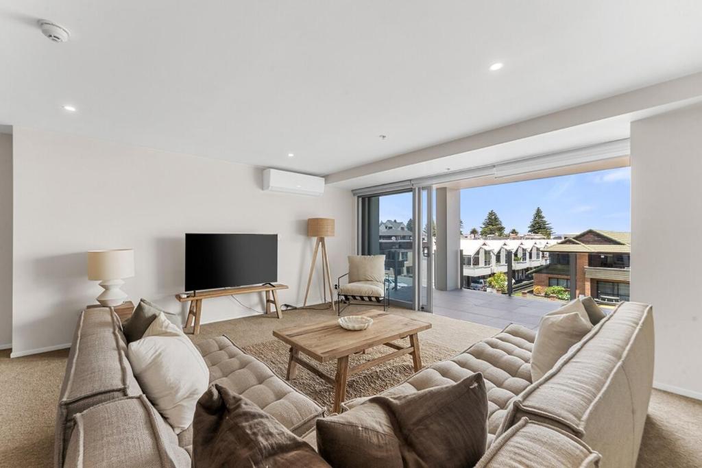 a living room with a couch and a table at Spacious apartment in Mount Maunganui in Mount Maunganui