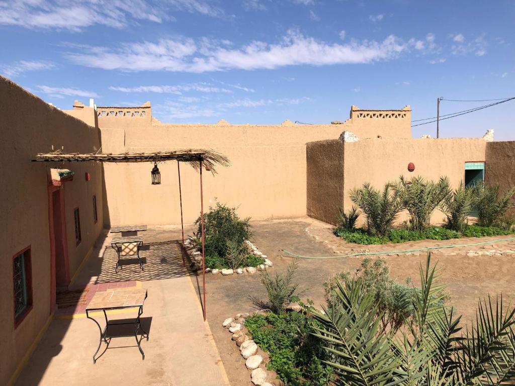 Un patio con una mesa y sillas frente a un edificio. en DAR MIRA DUNES Hassilabiad-Merzouga, en Adrouine
