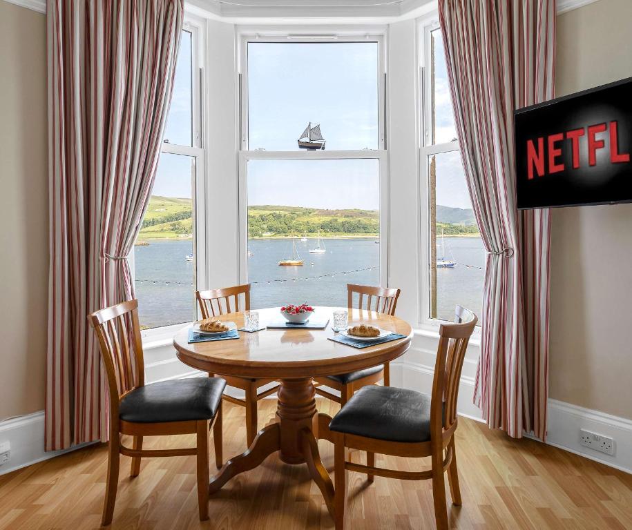 a dining room with a table and chairs and a large window at Above The Bay in Port Bannatyne