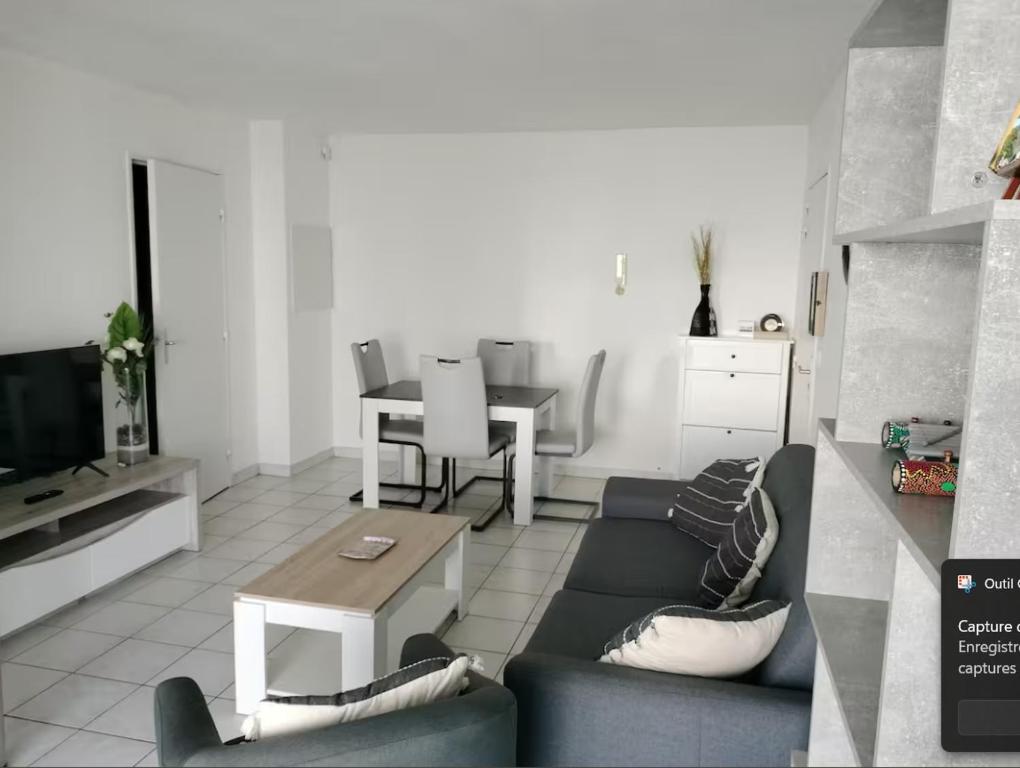 een woonkamer met een bank en een tafel bij Appartement avec parking privé in Aytré