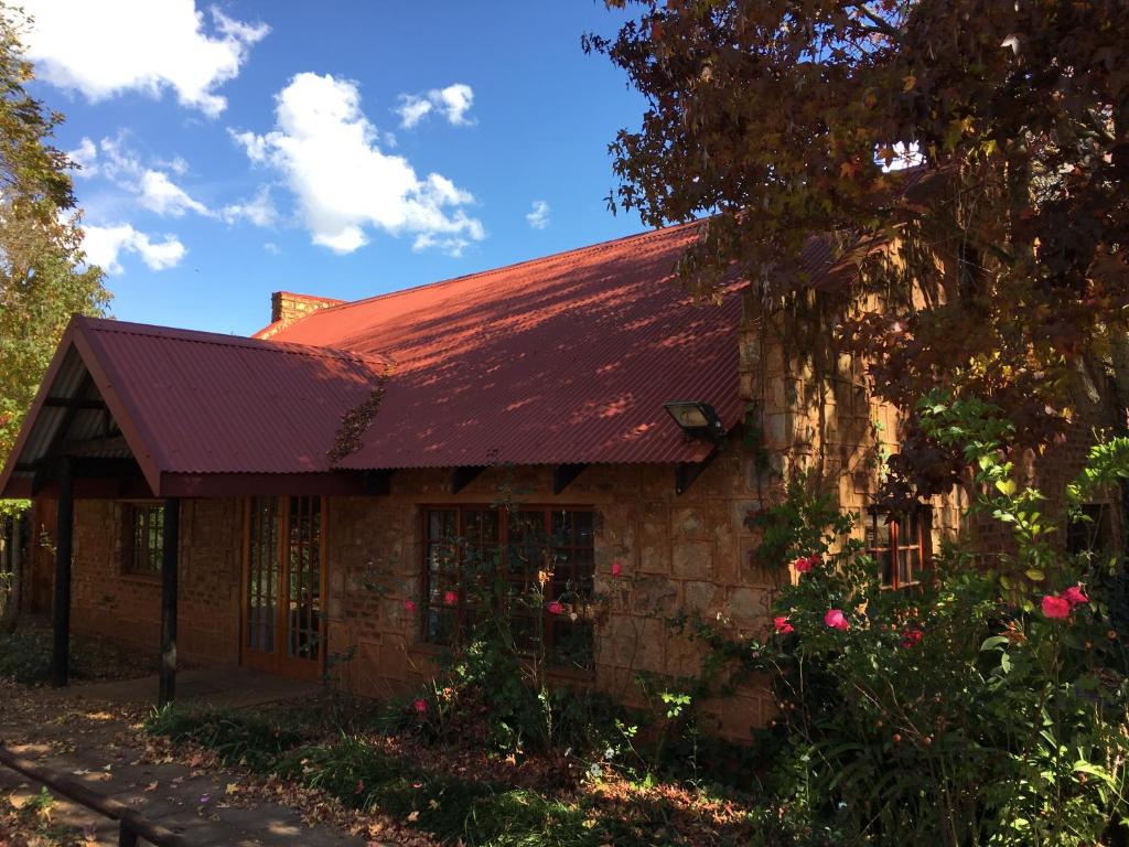 an old brick house with a red roof at Critchley Hackle - Managers Cottage in Dullstroom