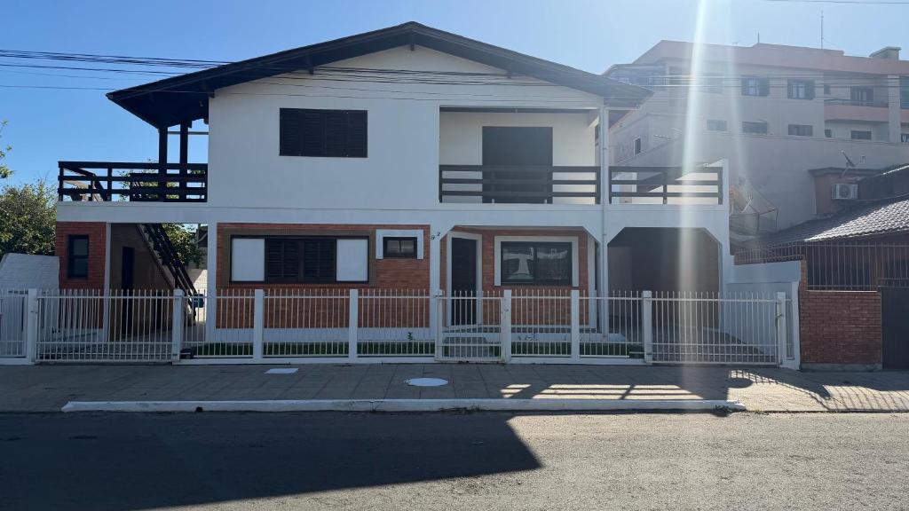 ein Haus mit einem weißen Zaun davor in der Unterkunft Prudêncio Casas de Temporada in Torres