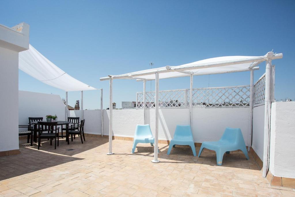 patio z 2 niebieskimi krzesłami i namiotem w obiekcie Apartamentos Diaber San Leandro w Sewilli