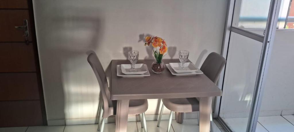 a table with chairs and a vase with flowers on it at Conforto e Lazer no Coração da Ilha de São Luís in São-José-do-Ribamar