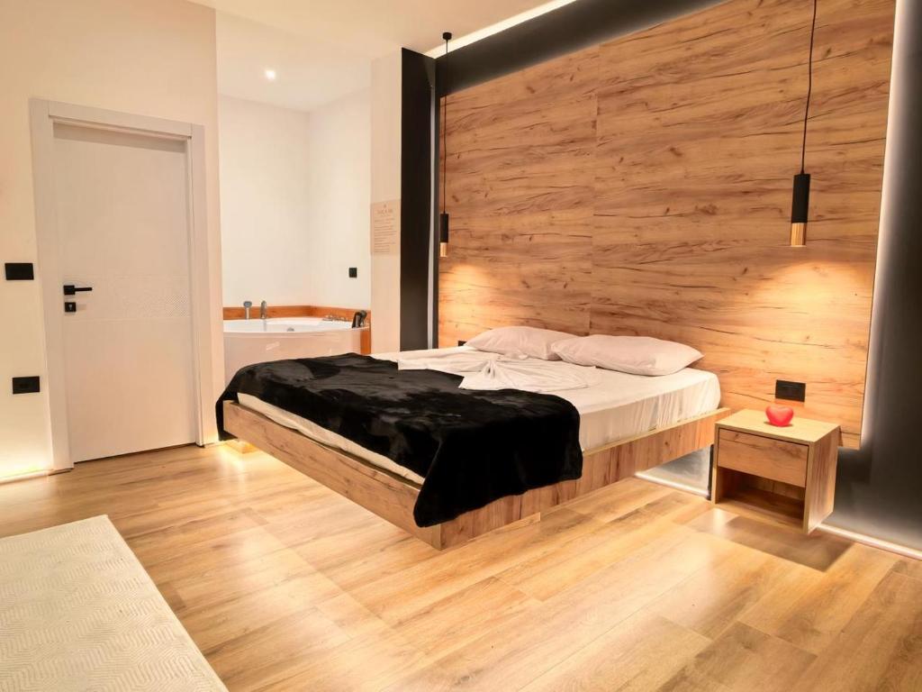 a bedroom with a bed with a wooden wall at Jacuzzi Studio Room in Shkodër