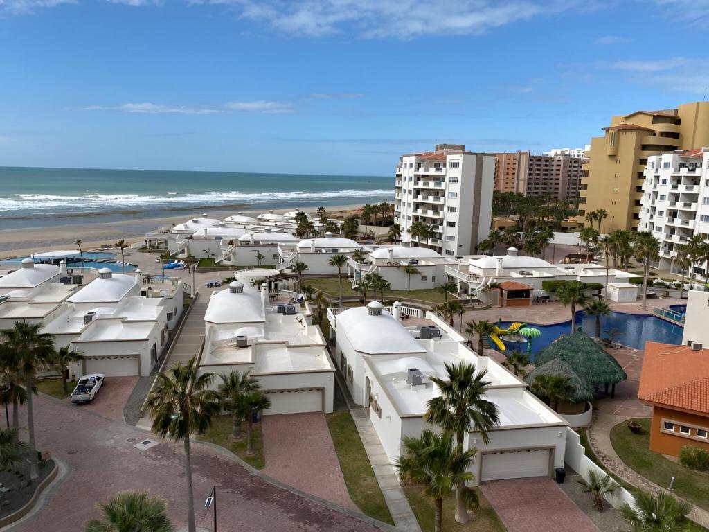 une vue d'une plage avec des bâtiments blancs et l'océan dans l'établissement Las Palmas Resort, à Puerto Peñasco