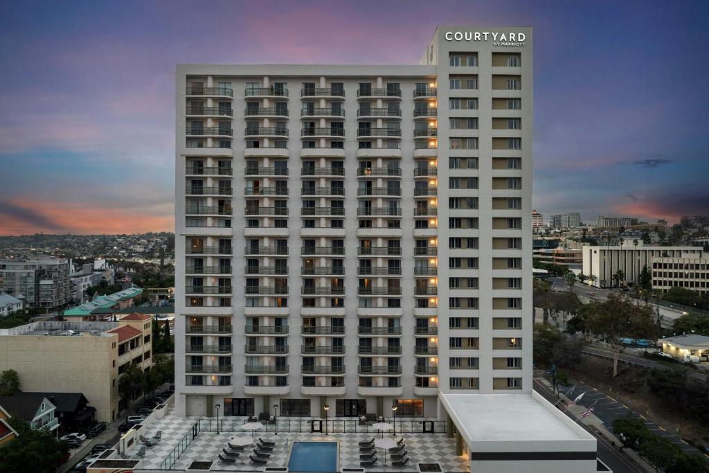 Courtyard by Marriott San Diego Downtown Little Italy في سان دييغو: مبنى أبيض طويل مع مسبح أمامه