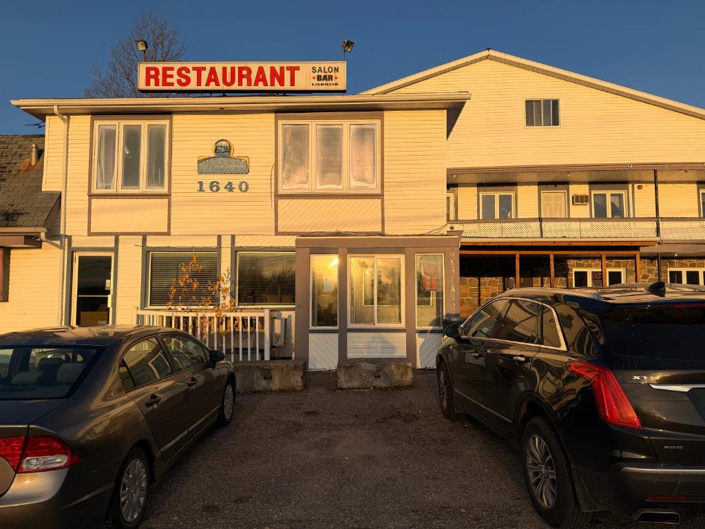 two cars parked in a parking lot in front of a restaurant at Auberge Canadienne in Temiscaming