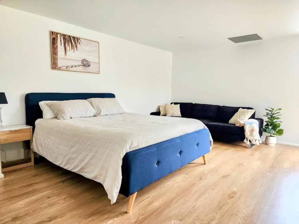 a bedroom with a blue bed and a couch at Quiet Peaceful Getaway with private backyard in Penrith