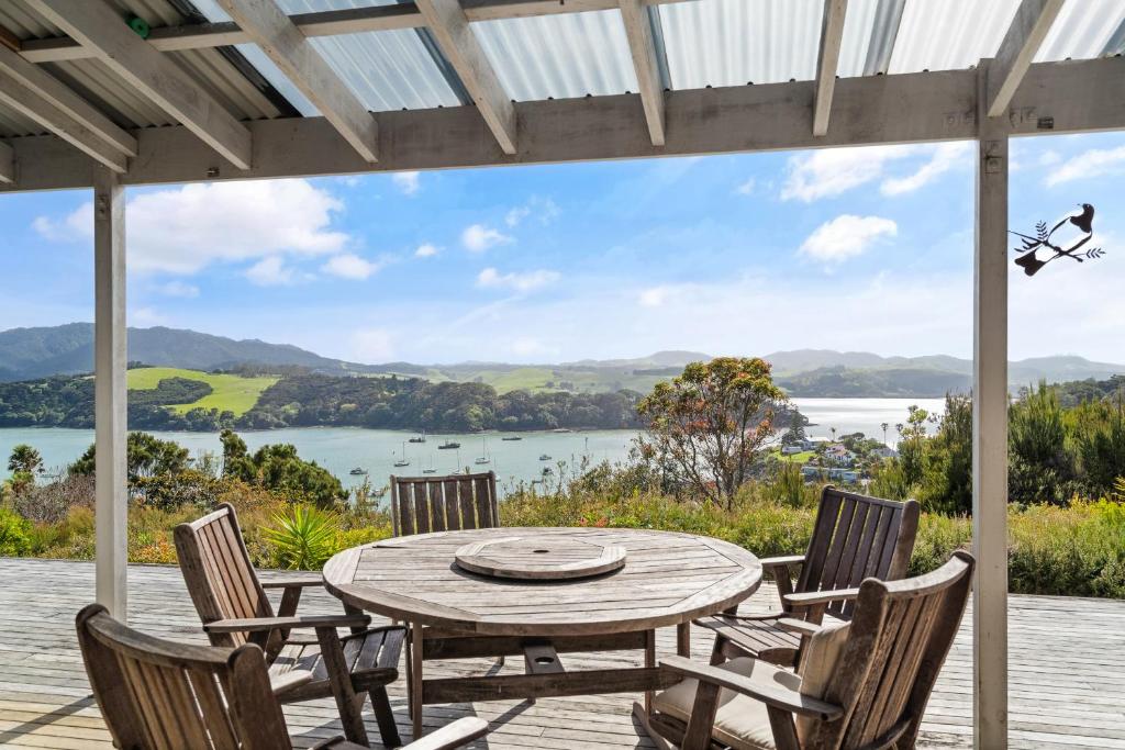 een tafel en stoelen op een terras met uitzicht op een meer bij Mangonui Ridge Retreat in Mangonui