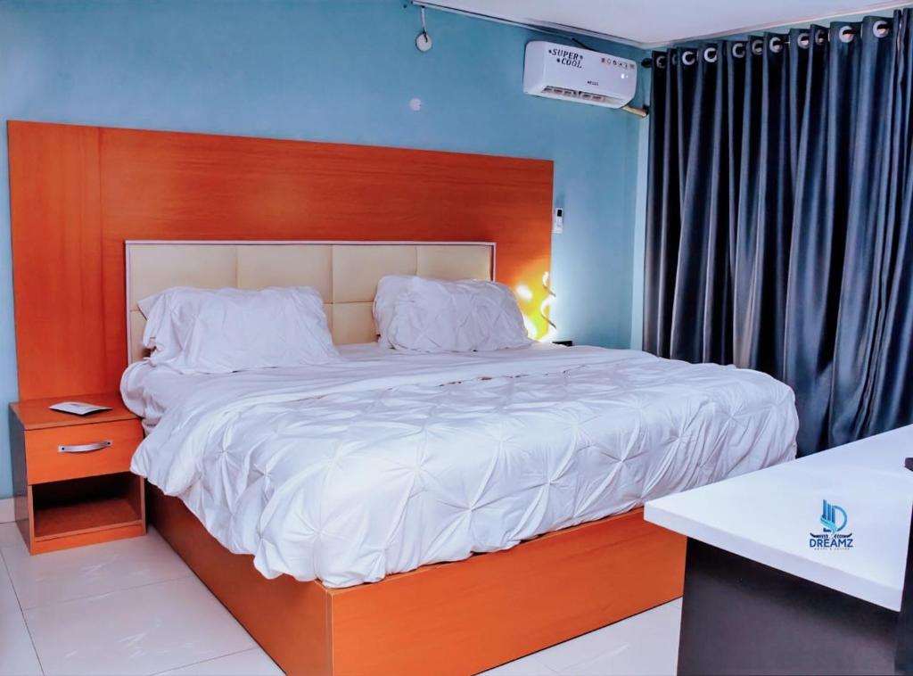 a bedroom with a large bed with a wooden headboard at Dreamz Hotel and Suites in Ogbomoso