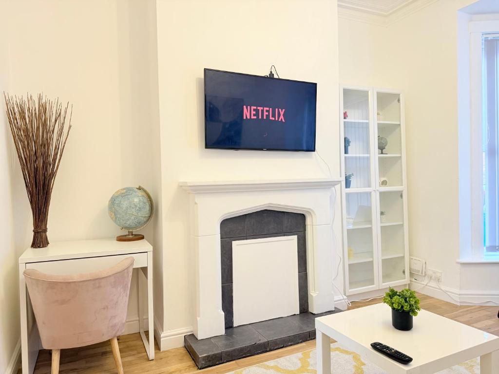 a living room with a tv above a fireplace at 4 bedrooms 8 beds Wi-FI smart tv games room in Hull