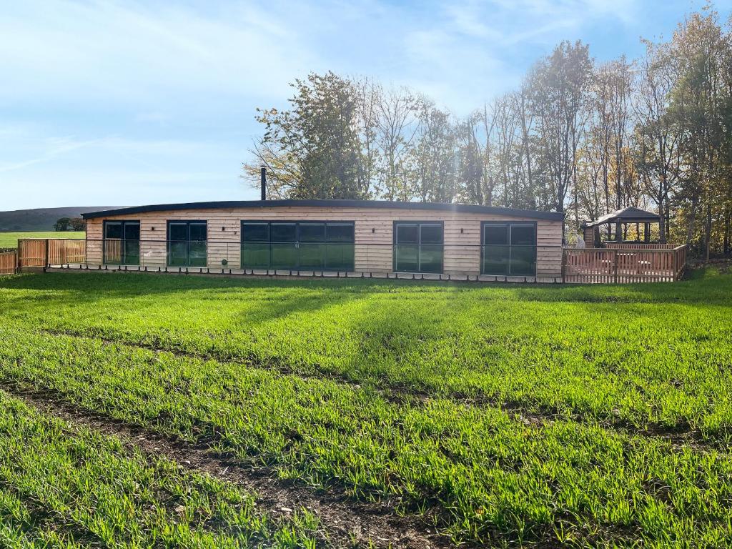 a house with a large field in front of it at Acre Luxury Lodges-Cedar Lodge in Evenjobb