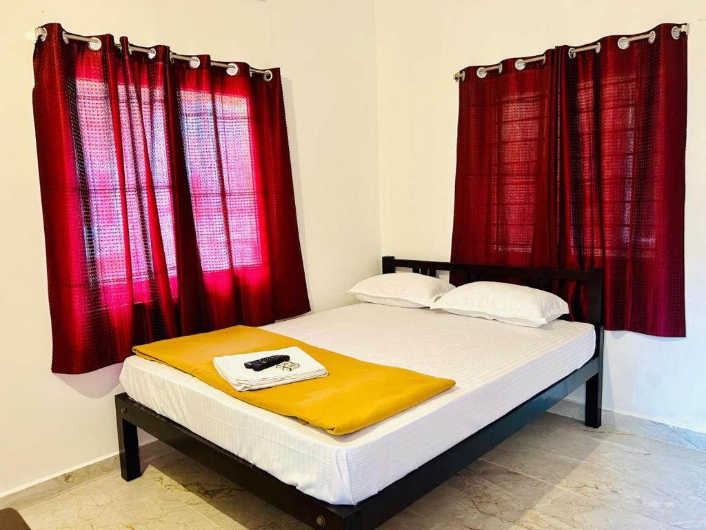 a bed in a room with red curtains at Auro Breeze Villa Inn in Puducherry