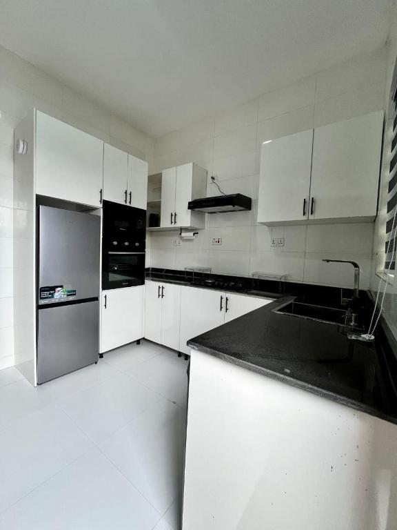 拉各斯DipNik Residence的白色的厨房配有白色橱柜和黑色家电