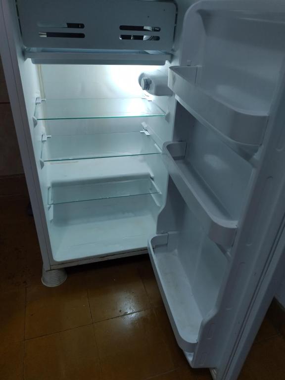 Un refrigerador vacío con la puerta abierta en una cocina. en Jorge 1, en Marcos Juárez