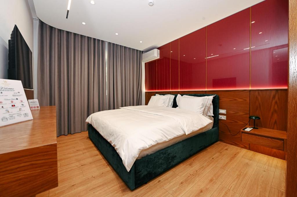 a bedroom with a bed with a red wall at Wilson On The Bllok in Tirana