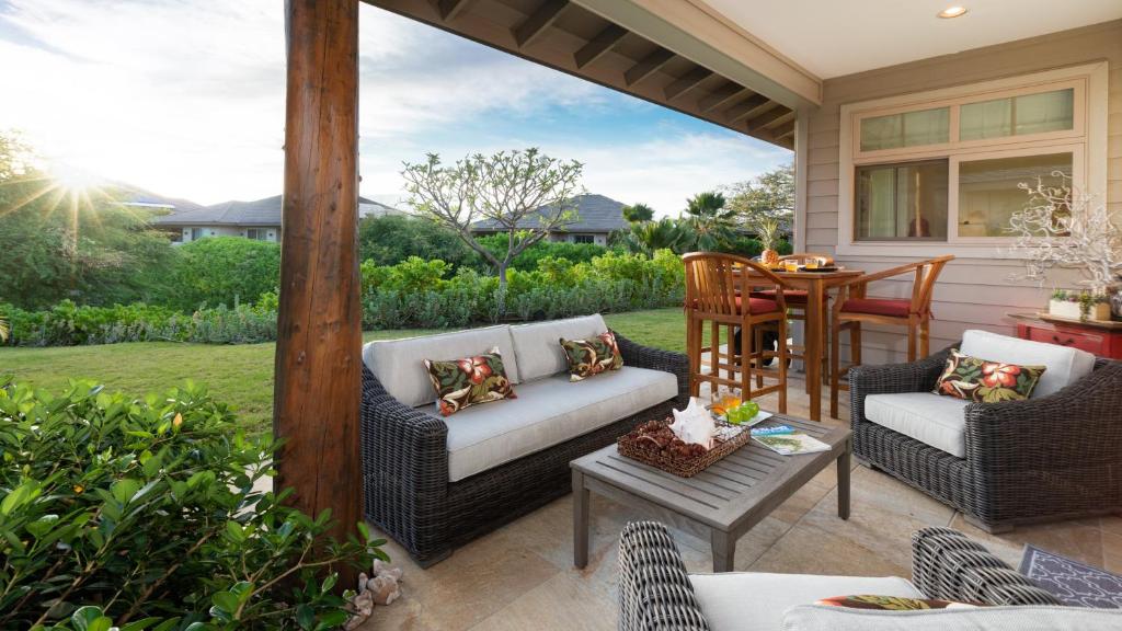 een patio met 2 rieten stoelen en een tafel bij WAHI MALU Comfortable 3BR Single-Level KaMilo Home Near Pool in Waikoloa