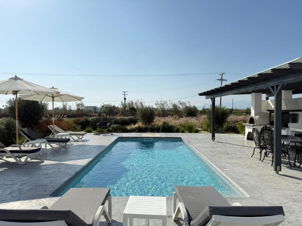 a pool with chairs and umbrellas in a yard at Villa Finoe 4 BDR with Private Pool in Plaka
