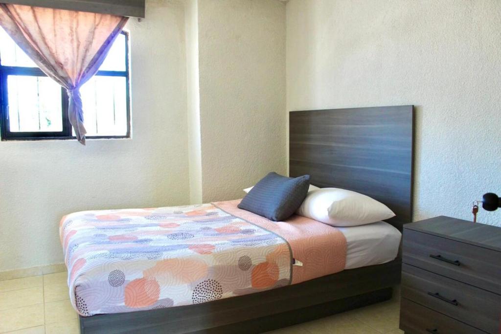 ein Schlafzimmer mit einem Bett, einer Kommode und einem Fenster in der Unterkunft departamento plus 1917 in Zacatlán